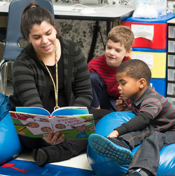 GPA female teacher with two young male students reading