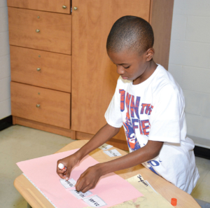 Young male students using scissors and glue to do hands-on math problems