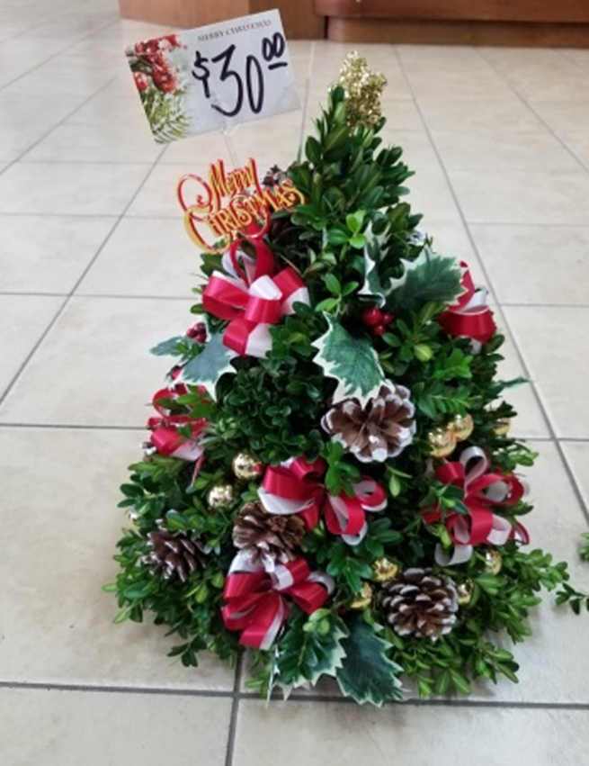 Boxwood Tree - $30 A traditional handcrafted boxwood tree decorated with festive ribbons, cones, glass balls & novelty ornaments all topped with a star.